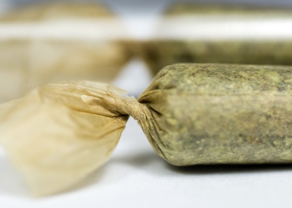 Close-up of a cannabis pre-roll joint on a clean surface.